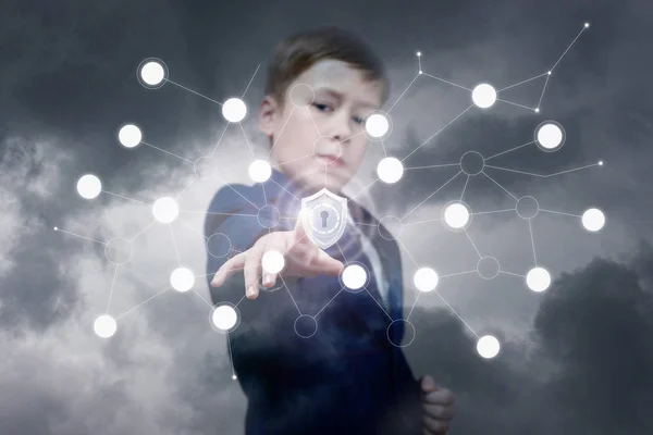 A confident officially dressed teenage child is pushing a shield inside a digital network system at the grey sky background. The concept is database and network protection and security.