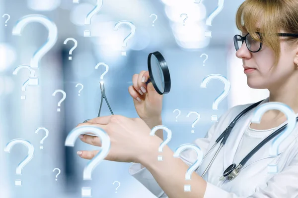 A close up of a doctor looking through a magnifier on the question mark in medical clamp standing at the blurred hospital room background. A concept of medical laboratory scientific discovery.