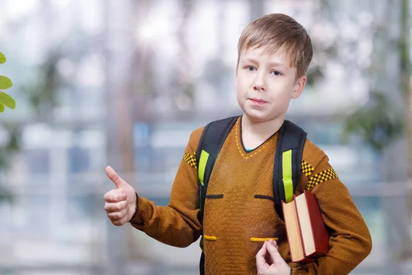 A pupil with school bag and text books showing a positive gesture.