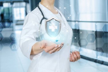 Bir doktor içinde tıbbi sembol olan bir kalkan gösteriyor..