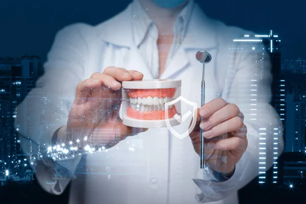 Un dentista que muestra un modelo de dentadura postiza y un espejo dental con signo de calidad delante de . —  Fotos de Stock