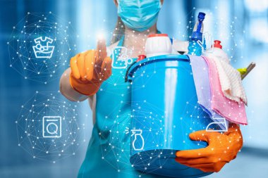 Temizlikçi kadın bulanık bir arkaplanda temizlik servisi simgesine tıklıyor.