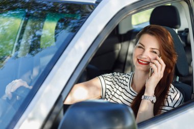 Araba kullanırken telefonla konuşan bir kadın..