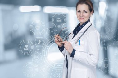 Bulanık bir arka planda, elinde gözlük olan kadın doktor..
