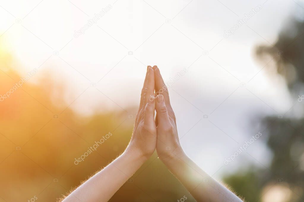 The concept of prayer.Hands folded for prayer on a blurred background.