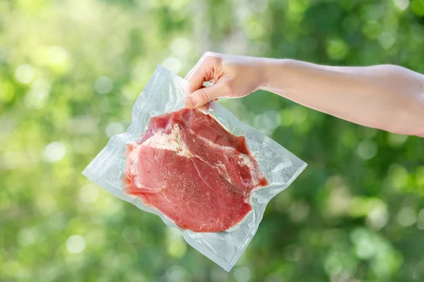 Hand shows packaged meat in a vacuum bag .