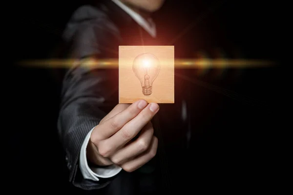 ビジネスにおけるアイデアの創造性の概念 ビジネスマンが電球を燃やしている小さなボードを示しています — ストック写真