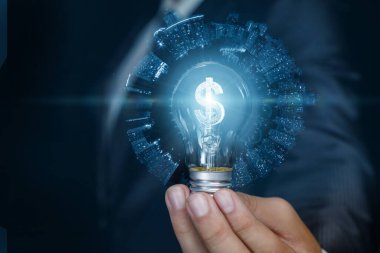 İş adamı mavi arka planda yanan dolar hologramı olan ampulü gösteriyor..