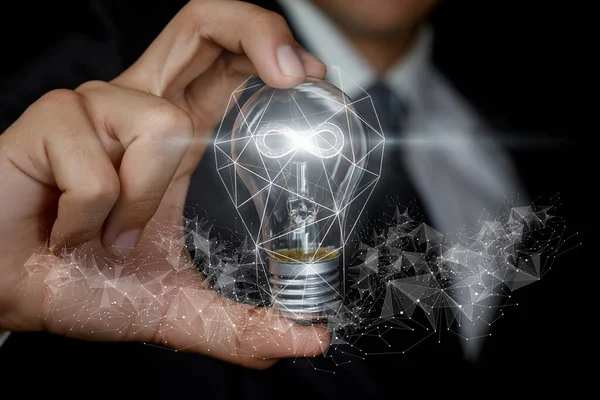 Endless business ideas concept. The hand shows a light bulb with a burning hologram of infinitie inside.