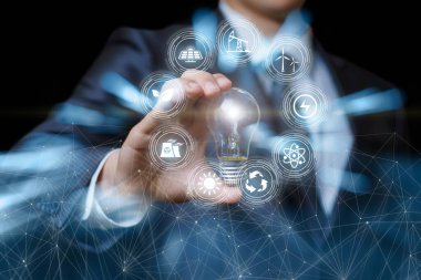 İş adamı bulanık arkaplanda yanan bir ampul ve alternatif enerji kaynakları gösteriyor.