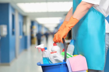 Temizlik personeli yoğun bir koridorda işe hazırlanıyor. Kendini işine adamış bir temizlikçi, işçiler arasındaki kalabalık koridoru düzenlemek için içi malzeme dolu bir kova tutuyor..