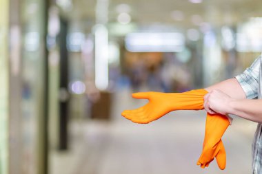 Ellerinde parlak eldivenlerle temizlik için hazırlanıyorlar. Bir insan kapalı bir alanda temizlik yapmadan önce parlak turuncu eldivenler giyer..