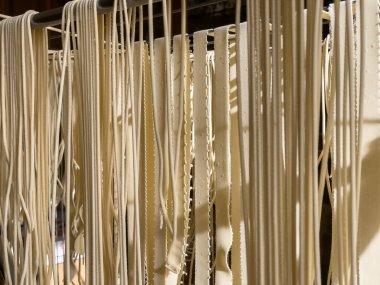 Mutfak ortamında taze erişte pişirmek. İnce hamurlar canlı bir mutfakta kurutulup erişte yapma sanatını sergilemek için sallanıyor..