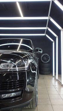 Temiz siyah bir araba, tekerlekler, lastikler, farlar. 