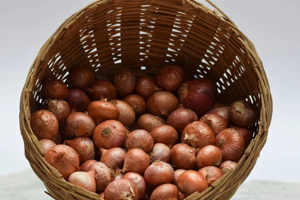 Small onions stored in round brown wicker bamboo basket in Indian and Pakistani household.