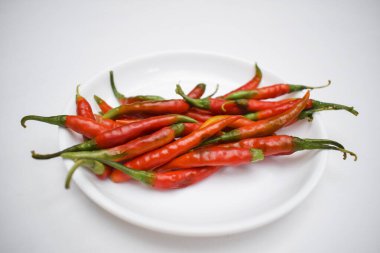 Taze yeşil biberler yeşil saplı kırmızı, olgun kırmızı biberlere dönüştü. Taze çiğ, beyaz arka planlı, kurutulmamış yerler. Sıcak Hint biberleri