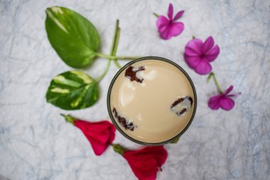 Lezzetli Süt (badam milk), badem ve safranla hazırlanmış süt, kurumuş gül yaprakları. Çiçekler ve yapraklarla süslenmiş..