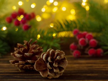 Noel ağacı kozalakları ladin içerikli, tahta arka planda Rowan meyveleri. Bokeh ışıkları ile sihirli arka plan bulanıklaştı. Noel konsepti, yeni yıl. seçili keskinlik.