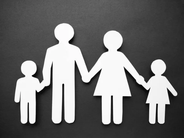 Símbolo de un hombre hecho de papel blanco sobre un fondo negro. El concepto de familia. Mamá, papá, hija e hijo . — Foto de Stock