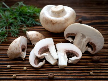 Kahverengi ahşap arka planda baharatlı ve yeşil dereotlu taze mantarlar. Yukarıdan görünüşü