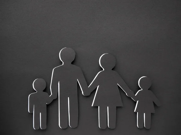 Человеческий символ, сделанный из черной бумаги на черном фоне. Понятие семьи. Мама, папа, дочь и сын — стоковое фото