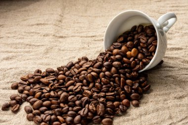 Kahve çekirdekleri kahve fincanından serpilmiştir.