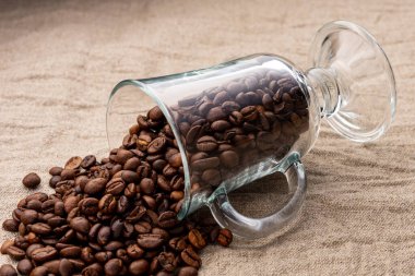 Şeffaf bir cam kadehten kahve çekirdekleri serpilmiş.