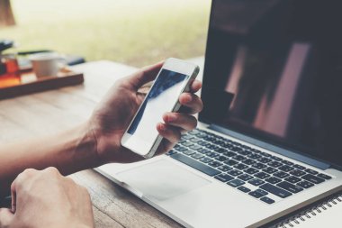 Telefonu ve laptop üzerinde ahşap masa holding iş adamı. Tonda vintage.
