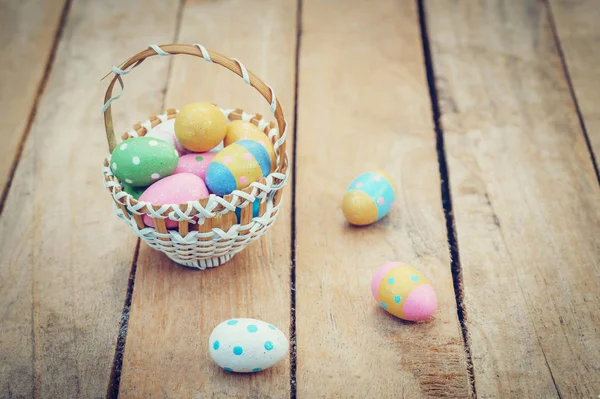 Colorful easter eggs in basket on wooden table win copy space.