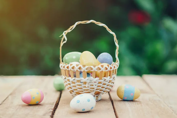 Colorful easter eggs in basket on wooden table win copy space.