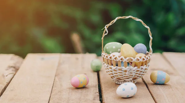 Colorful easter eggs in basket on wooden table win copy space.