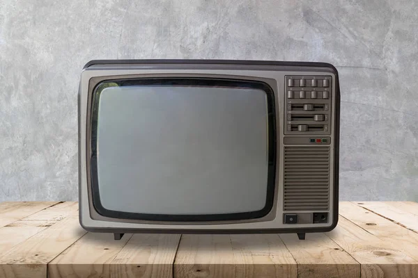 Vintage television on wooden table and cement wall texture and background.