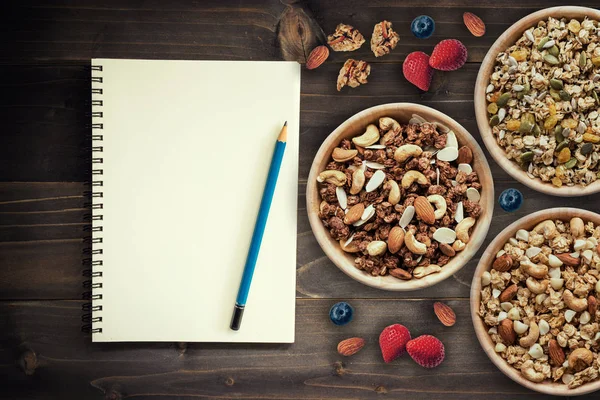 Domácí müsli a čerstvé bobule na dřevěného stolku s knihou poznámek, — Stock fotografie