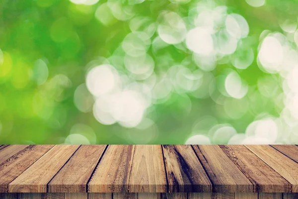Пустой деревянный стол и абстрактные размытые зеленые листья боке — стоковое фото