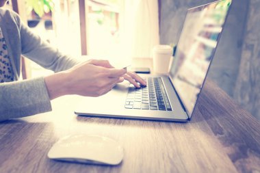 Asya kadın kullanarak laptop bilgisayar yapmak online aktivite ödeme kredi kartı üzerinde ahşap masa at ev ofis.
