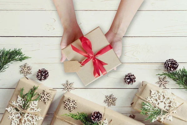 Mujer sosteniendo la mano regalos de Navidad caja de regalo en una mesa de madera — Foto de Stock