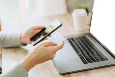 Kafede internet üzerinden alışveriş yapmak için akıllı telefon ve kredi kartı kullanan kadın.