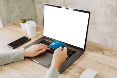 Kredi kartı tutan ve internetten alışveriş yapan bir kadın.