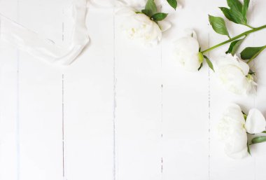 Stok fotoğraf tarz. Beyaz peonies çiçekler ve eski beyaz ahşap zemin üzerinde ipek kurdele ile kadınsı düğün tablo kompozisyon. Boş alanı. Üstten görünüm. Resmi blog için.