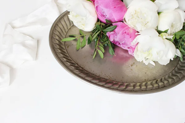 Foto de estoque estilo. Composição de mesa de casamento ou aniversário feminino com buquê floral. Flores de peônias brancas e rosa na velha bandeja de prata vintage e fita de seda. Fundo branco. Imagem para blog . — Fotografia de Stock