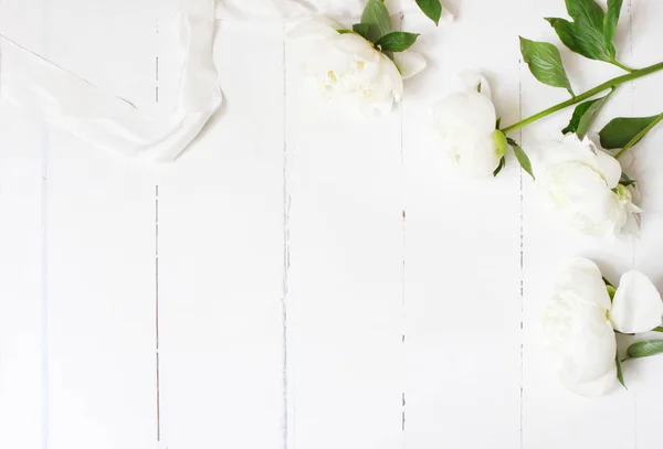 Photo de stock stylisée. Composition de la table de mariage féminine avec des fleurs de pivoines blanches et un ruban de soie sur un vieux fond en bois blanc. Espace vide. Vue de dessus. Photo pour blog . — Photo