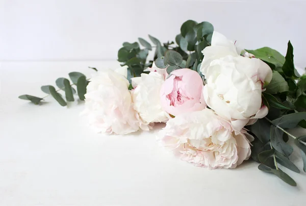 Zdjęcie w stylu. Martwa natura ozdobny kompozycji kwiatowych. Ślubu lub urodzin bukiet kwiaty różowe i białe piwonia i gałęzi eukaliptusa. Biały stół tło. — Zdjęcie stockowe