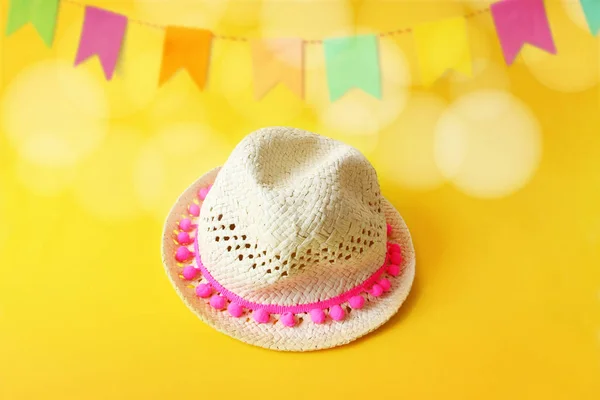 Festa Junina, Brazilian June party greeting card, invitation with straw hat and blurred yellow background with bunting flags decoration and bokeh lights. Festive design. Stock Picture