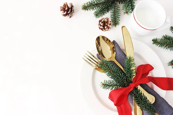 Local de mesa de Natal tradicional. Talheres dourados, guardanapo de linho, ramos de abeto e xícara de leite. Cone de pinheiro e decoração de fita vermelha. Fundo de férias. Flat lay, vista superior com espaço de cópia . — Fotografia de Stock