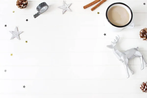 Composición navideña. Chocolate caliente, conos de pino, palitos de canela, estrellas de confeti y renos sobre fondo de mesa blanco. Concepto creativo de vacaciones de invierno. Piso tendido, vista superior —  Fotos de Stock