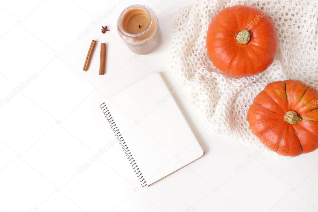 Autumn cozy composition. Mockup scene with blank notebook. Pumpkins, candle, cinnamon sticks and knitted plaid on white table background. Thanksgiving, fall, halloween concept. Flat lay, top view.
