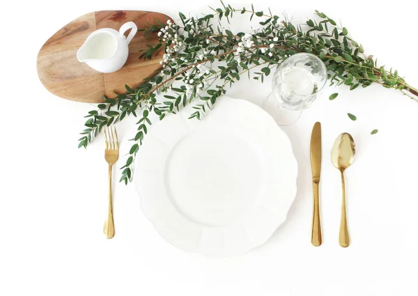 Casamento festivo, mesa de aniversário com talheres dourados, eucalipto parvifolia, copo de vinho e jarro de leite. Mockup placa de porcelana vazia. Conceito de menu de restaurante rústico. Deitado plano, vista superior — Fotografia de Stock