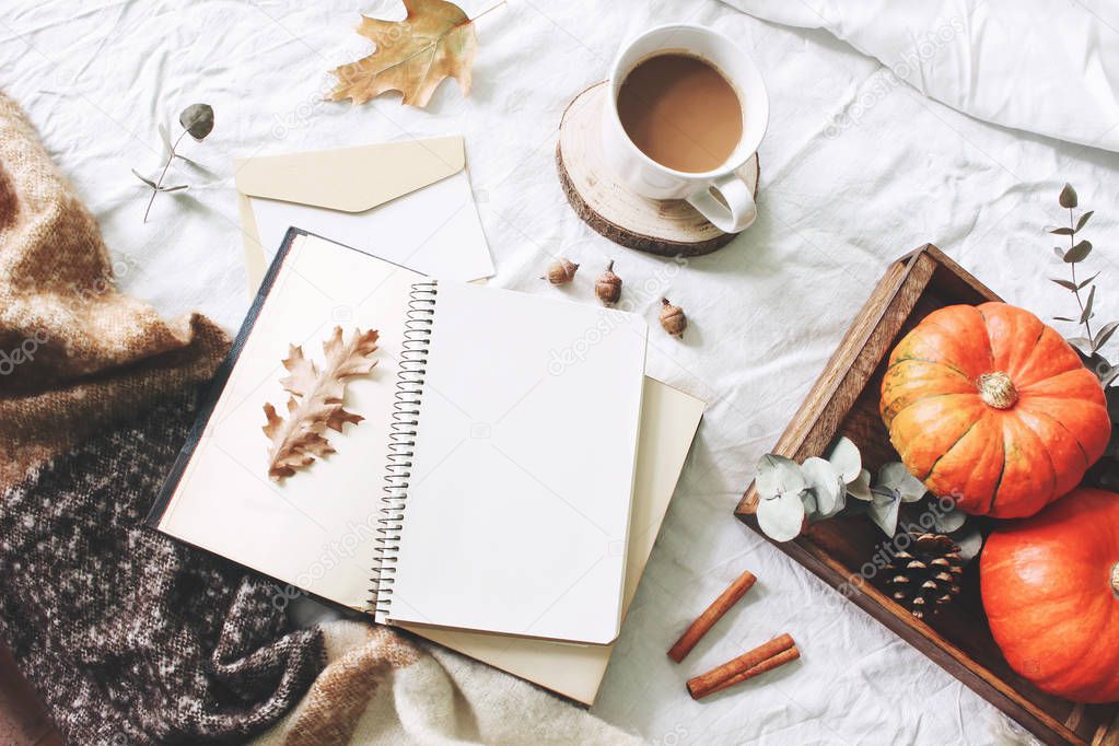 Autumn breakfast in bed composition. Card, notebook mockup. Cup of coffee, eucalyptus leaves, pumpkins on wooden tray. White linen background. Thanksgiving, halloween concept. Flat lay, top view.