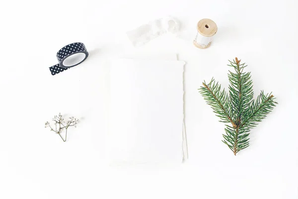 크리스마스, 겨울 결혼식 데스크톱 편지지 모형 장면입니다. 빈 인사말 카드, 봉투, 검정 종이 테이프, 실크 리본 및 녹색 스프루 스 나무 가지. 화이트 테이블 배경입니다. 평면 위치, 최고 보기. — 스톡 사진