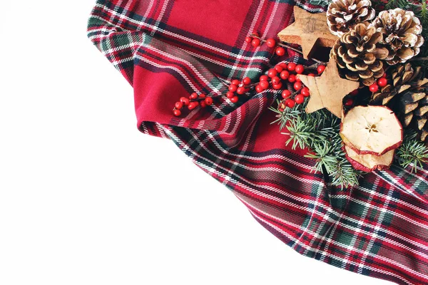 크리스마스 축제 구성 스타일. 겨울 꽃 배열입니다. 소나무 콘, 전나무 나무 가지, 붉은 홀리 열매와 나무 별 체크 무늬 타탄 무늬에. 화이트 테이블 배경입니다. 평면 위치, 최고 — 스톡 사진
